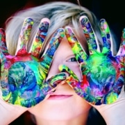 Kind malt mit bunten Händen, was kreative und fürsorgliche Kinderpflege zu Hause darstellt.